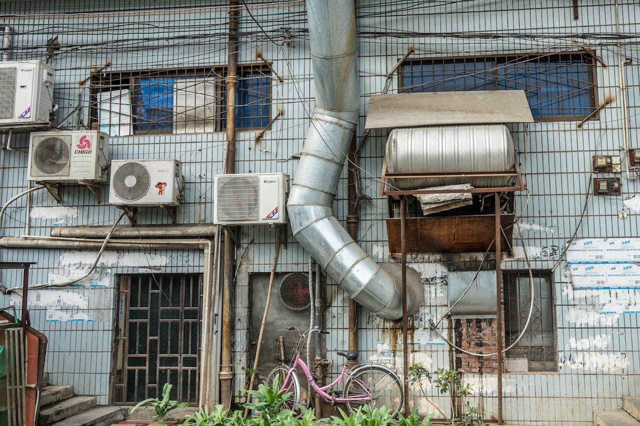 An urban building facade featuring multiple air conditioning units and ductwork.